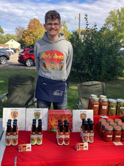Nikoli standing behind his hot sauce at a farmers market
