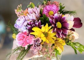 yellow,pink, and purple flowers in a small glass vase.