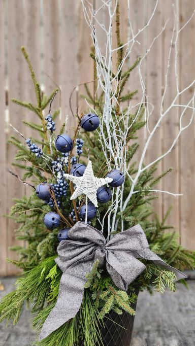 Silver bow on a spruce top pot with blue bells, white star, blue berry bunch and white branches