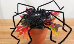 a black spider crafted from a mum, fall leaves, and ceramic pot